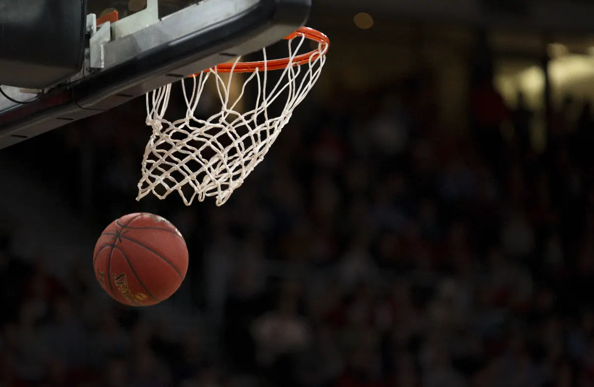 Basketball at the rim under floodlights